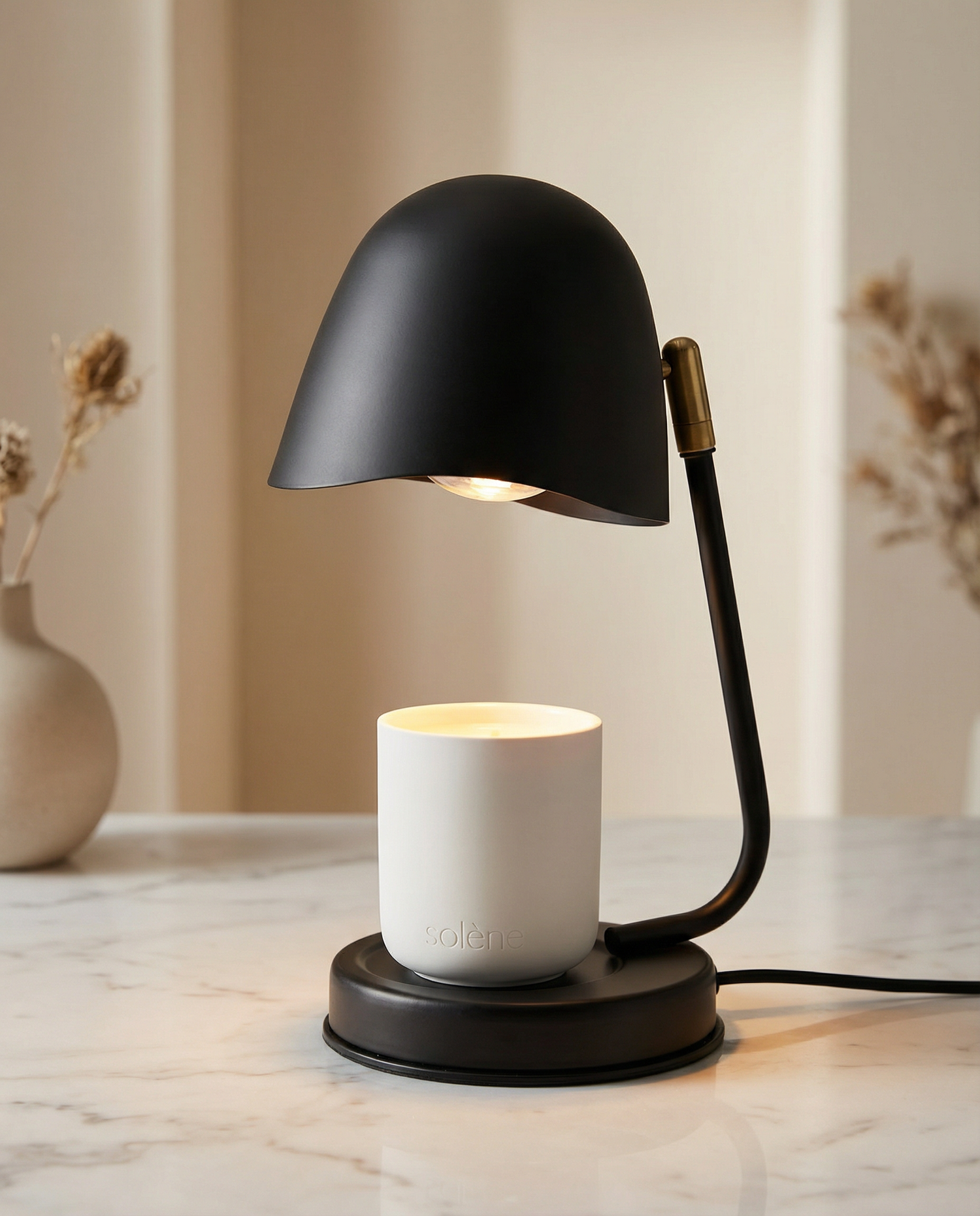 Black candle warmer lamp with a white candle on a marble surface