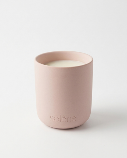 A pastel pink candle with 'Solene' branding on a white background